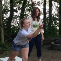 2 women smiling and playing cornhole